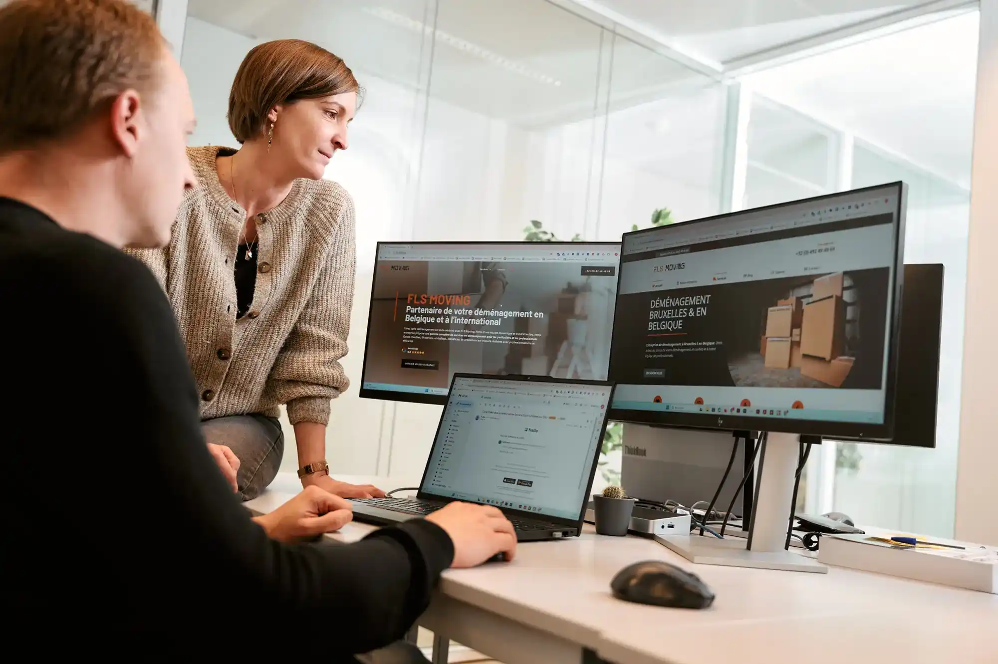 Deux webdesigners assis devant trois écrans