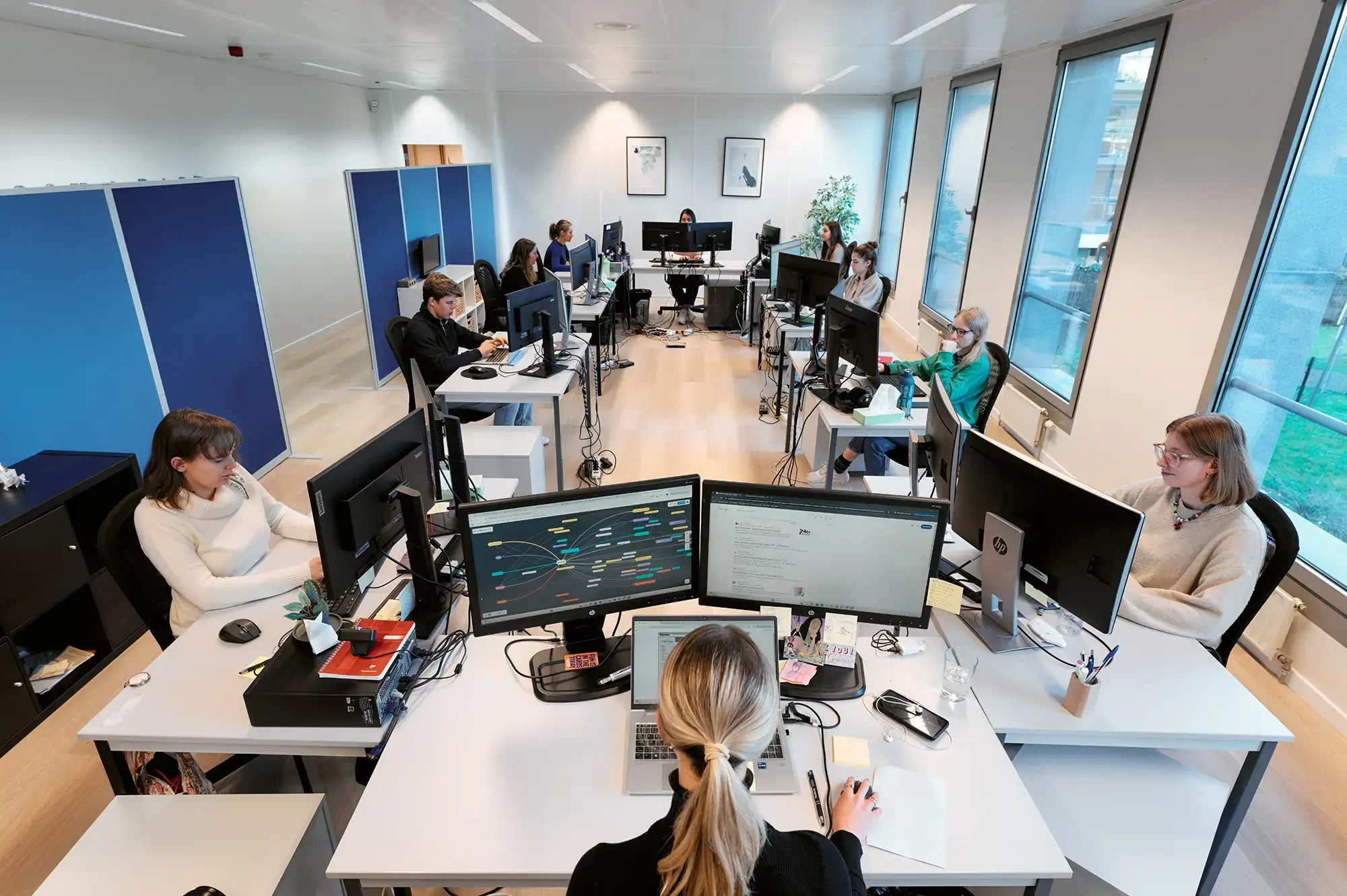 Vue sur les dix bureaux occupés de l’open space Production