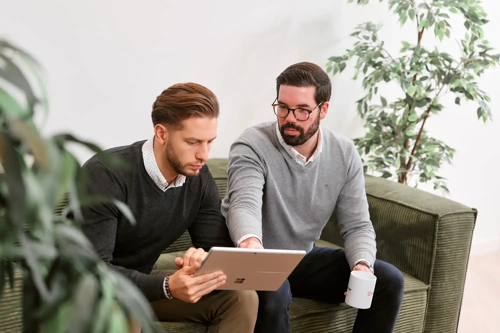 Deux commerciaux assis naviguent sur une tablette